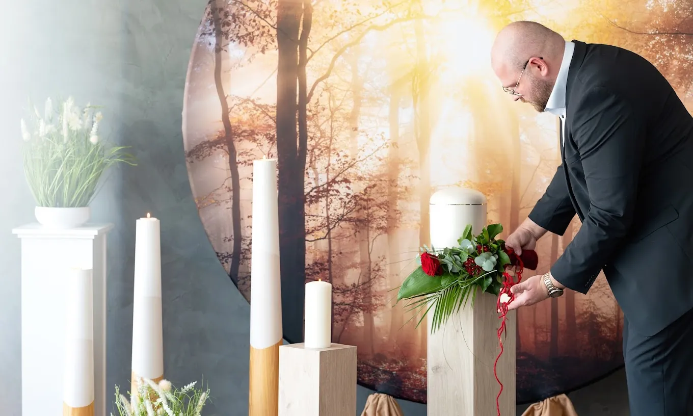 Ein Mitarbeiter von Wiegmann & Maaz richtet Blumenschmuck an einer Urne
